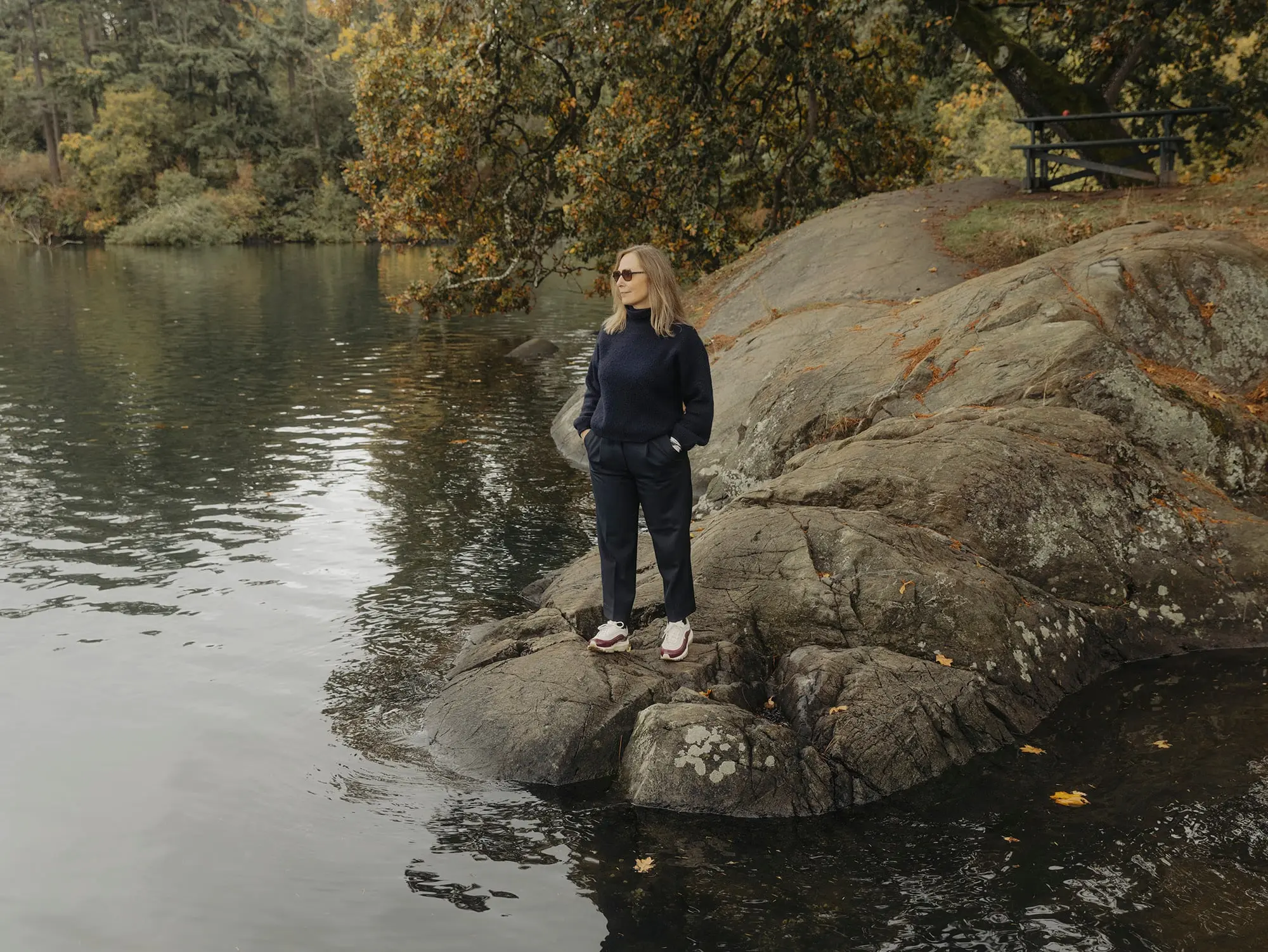 Landscape shot of a women standing on a rock while looking at the river