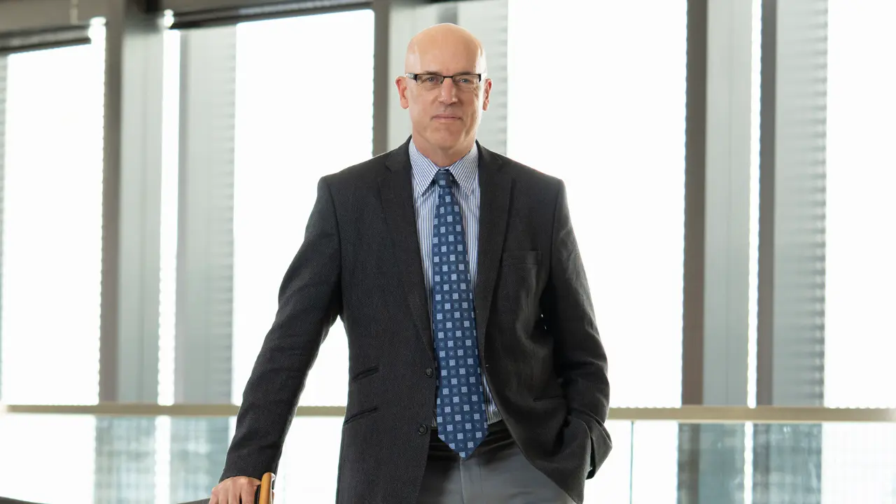 Dr. Michael Hill stands in front of a bright window.