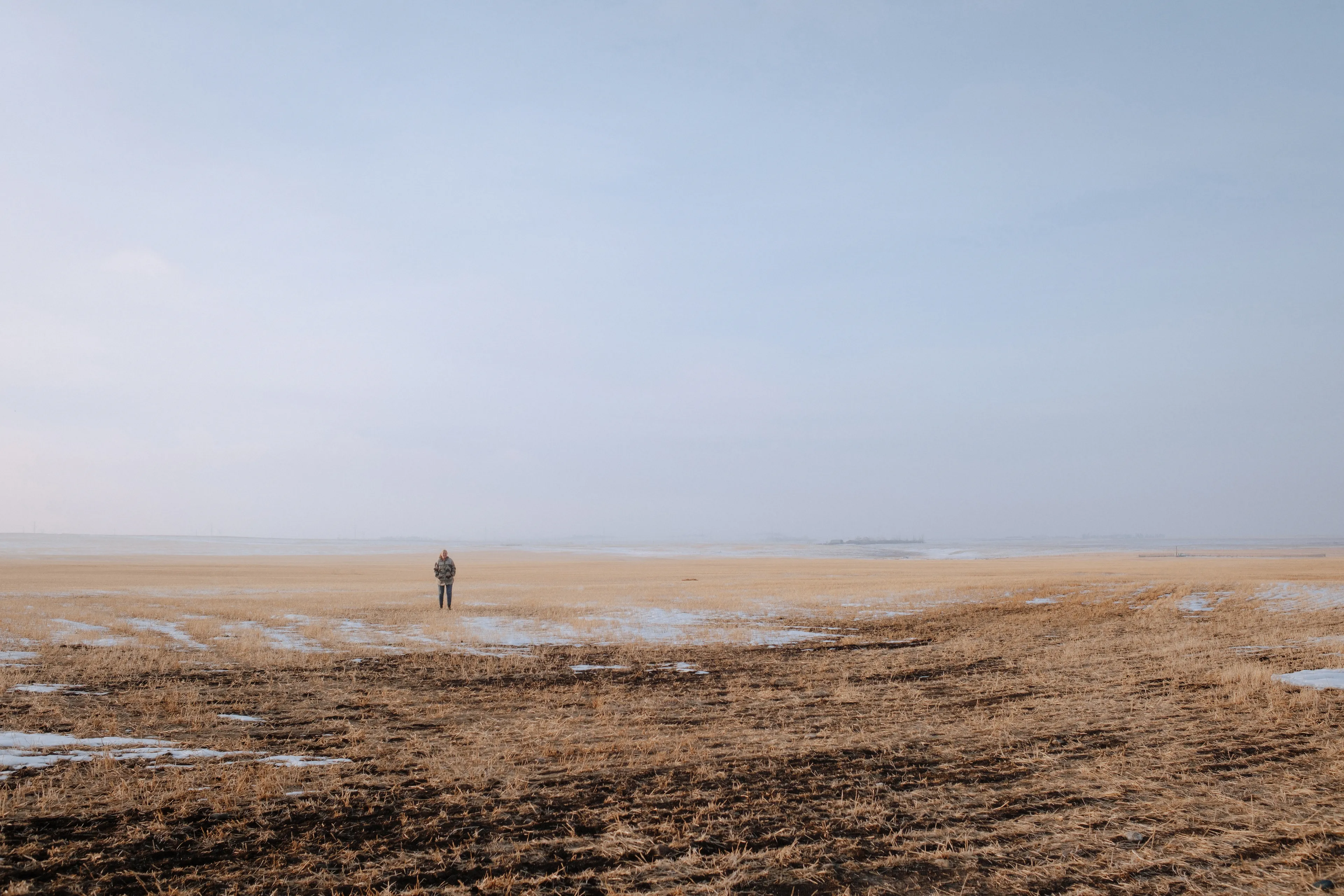A tiny person standing in a vast agricultural landscape