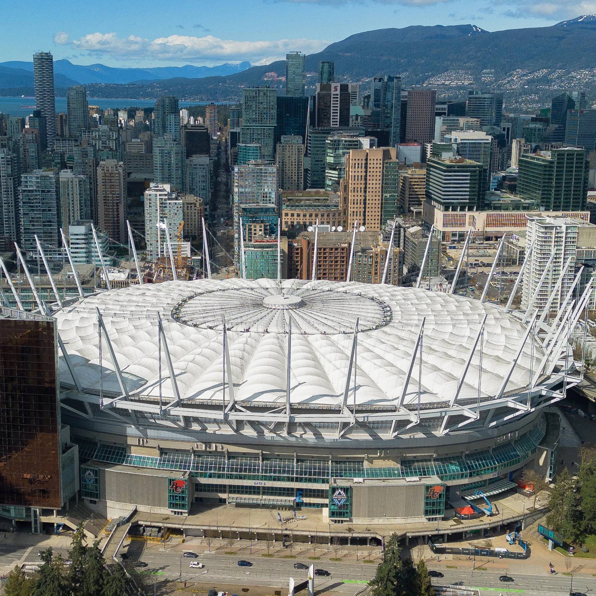 Wide, aerial shot of the BC Place, with buildings and the mountains in the background.
