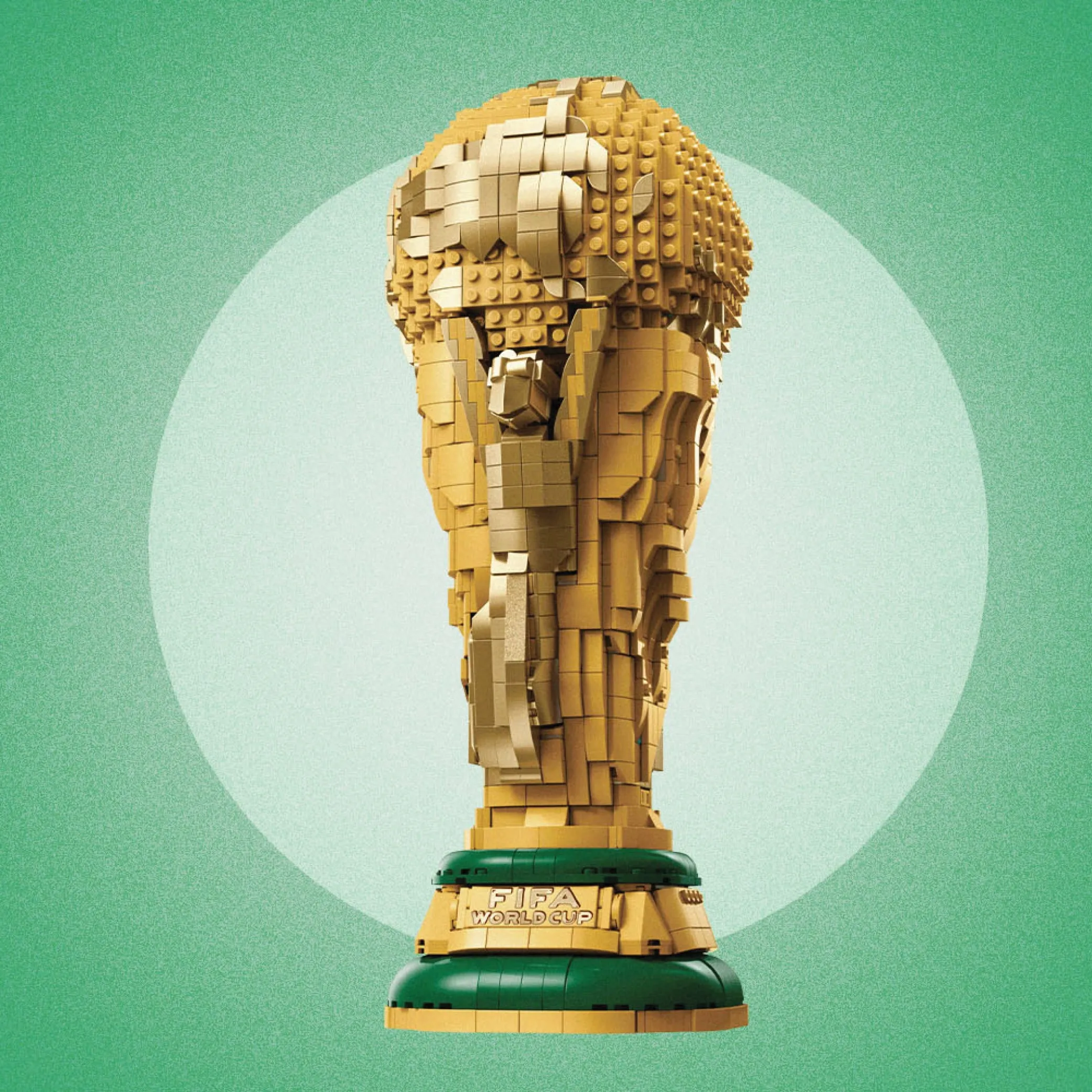 A golden replica of World Cup trophy made of LEGO blocks on the light green coloured background.