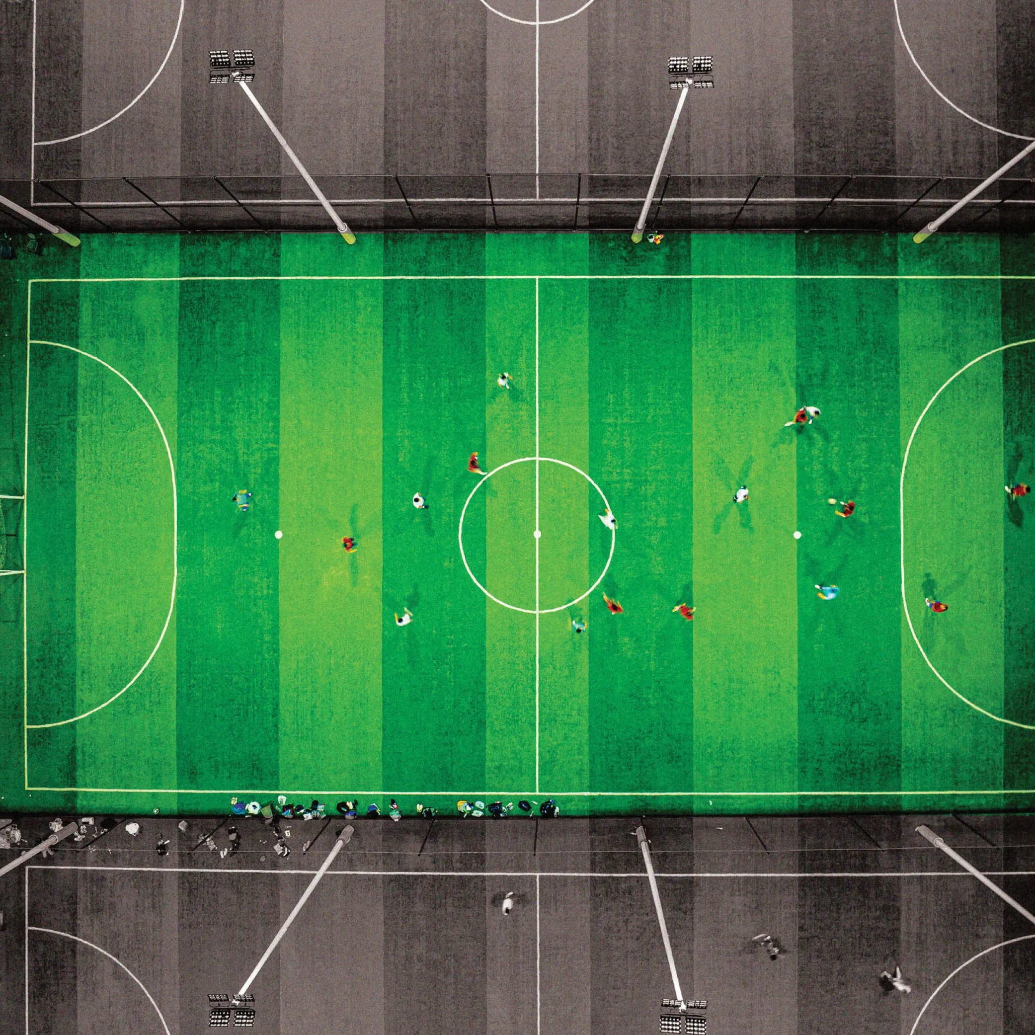 A mini soccer pitch captured directly from above. People are playing in the field.