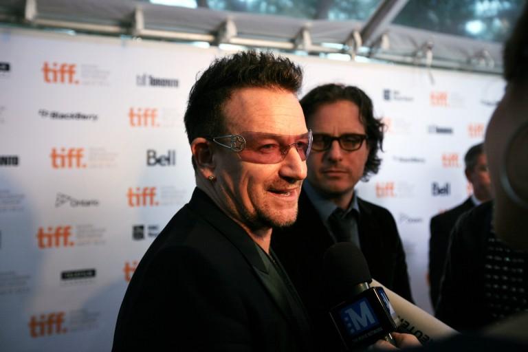 <p><strong>September 8, 2011:</strong> U2&#8217;s Bono is interviewed by TV reporters at Roy Thompson Hall for the Opening Night Gala premiere of <em>From The Sky Down</em> at the Toronto International Film Festival. Davis Guggenheim is seen in the background. (Kara Dillon/Maclean&#8217;s)</p>
