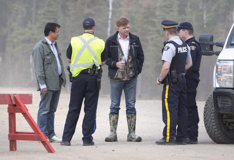 <p>Alberta Wildrose Leader Brian Jean, centre, talkswith police near a wildfire in Fort McMurray, Alta., on Thursday, May 5, 2016. Jean&#8217;s house was burned down in the fire. (Jason Franson/CP)</p>
