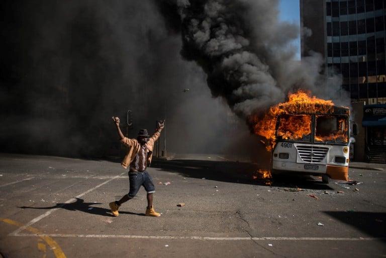 <p>A student gestures near a burning bus during clashes with riot police following a protest over University tuition fees on October 10, 2016 in Johannesburg.<br />
South African student protesters and police clashed in renewed violence in Johannesburg as attempts to re-open Wits University descended into running battles on campus. Protesters throwing rocks were dispersed by riot police using tear gas, rubber bullets and stun grenades as pressure ratchets up on campuses across the country over tuition fees. (Mujahid Safodien/AFP/Getty Images)</p>
