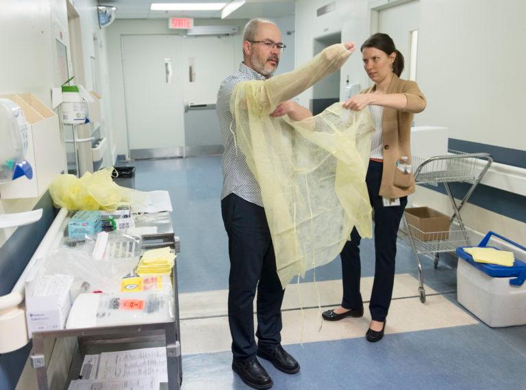 Health workers demonstrate how to put on protective clothing during a tour of a COVID-19 evaluation clinic in Montreal on March 10, 2020 (Graham Hughes/CP)