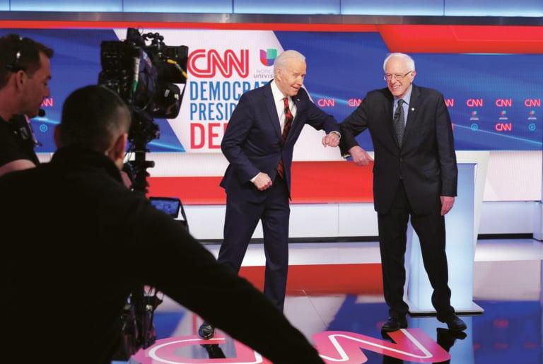 Biden and Sanders bump elbows at a March 16 Democratic debate with no studio audience (MANDEL NGAN/AFP via Getty Images)