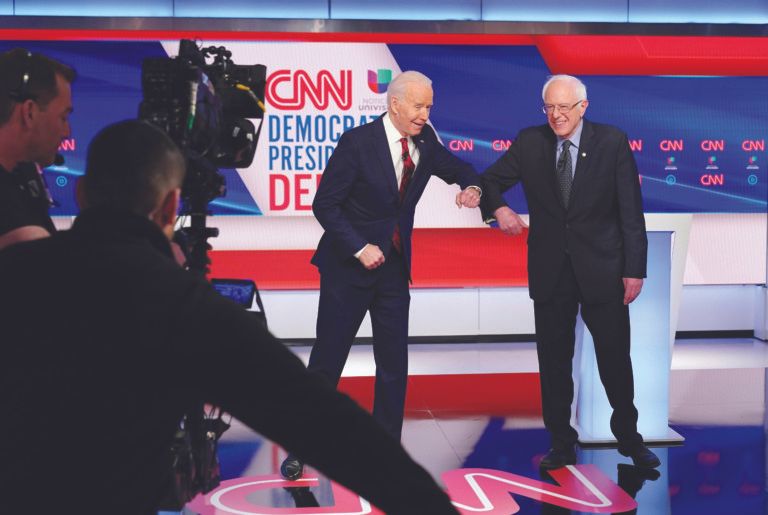 Biden and Sanders bump elbows at a March 16 Democratic debate with no studio audience (MANDEL NGAN/AFP via Getty Images)