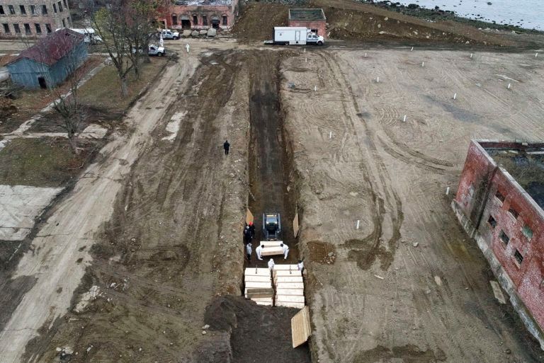 Workers bury bodies in a trench on Hart Island, N.Y. (John Minchillo/AP/CP)