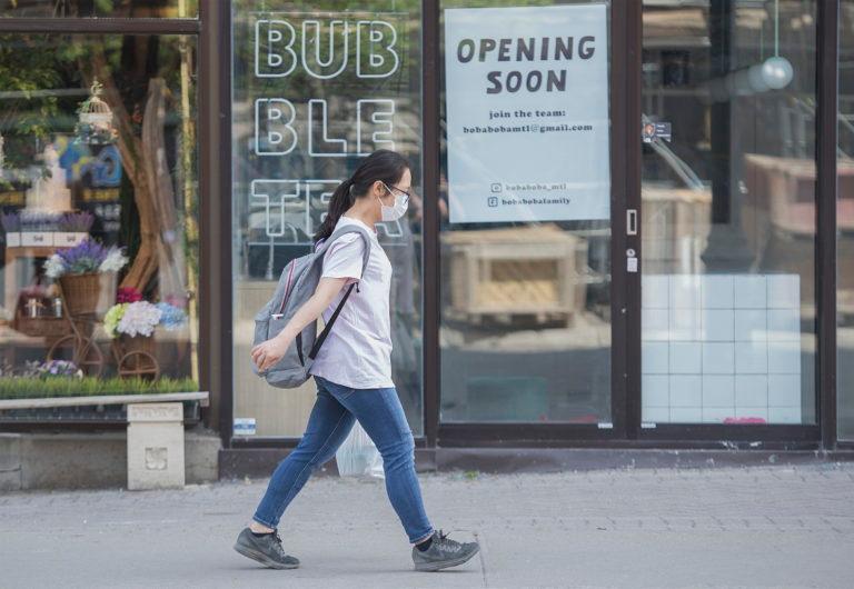 A woman wears a face mask as she walks along Sainte-Catherine street in Montreal, Sunday May 24, 2020, as the COVID-19 pandemic continues in Canada and around the world. Stores with a street entrance are allowed to reopen in Montreal on May 25th. THE CANADIAN PRESS/Graham Hughes