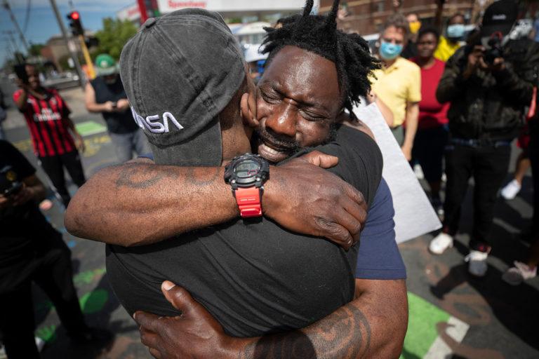 Former NFL player Tyrone Carter hugs a protester at the site where George Floyd was killed (Jerry Holt/Star Tribune/ Getty Images)