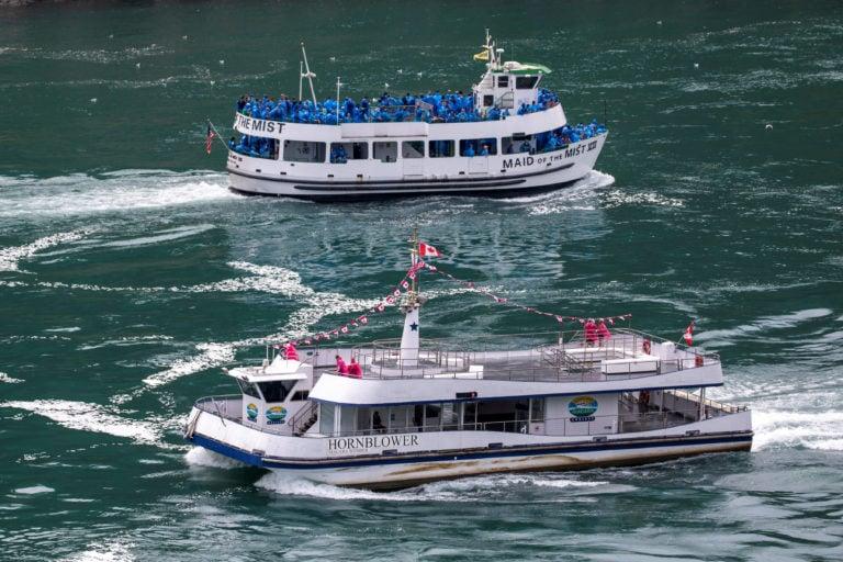 American tourist boat Maid Of The Mist, limited to 50% occupancy under New York state's rules amid the spread of the coronavirus disease (COVID-19), glides past a Canadian vessel limited under Ontario's rules to just six passengers, in Niagara Falls, Ontario, Canada July 21, 2020. (Carlos Osorio/Reuters)