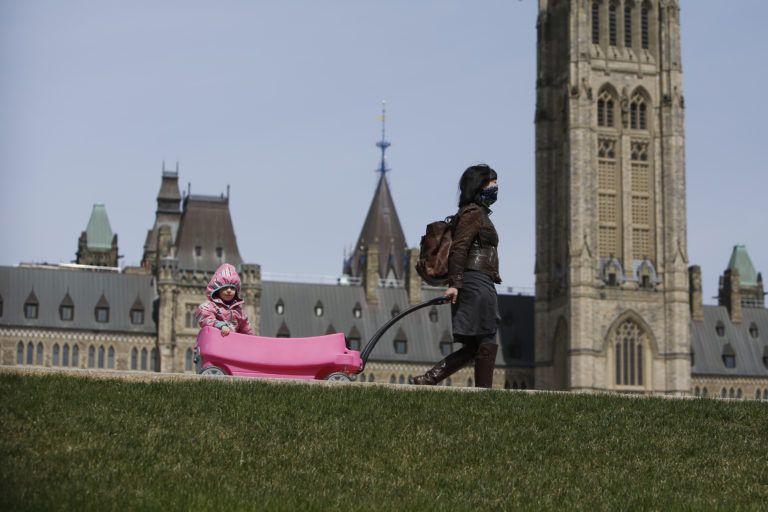 A woman wearing a protective mask pulls a wagon carrying her daughter along the grounds of Parliament Hill in Ottawa, Ontario, Canada, on Wednesday, April 29, 2020. Prime Minister Trudeau said that the government will do what's needed to protect supply chains. Photographer: David Kawai/Bloomberg via Getty Images