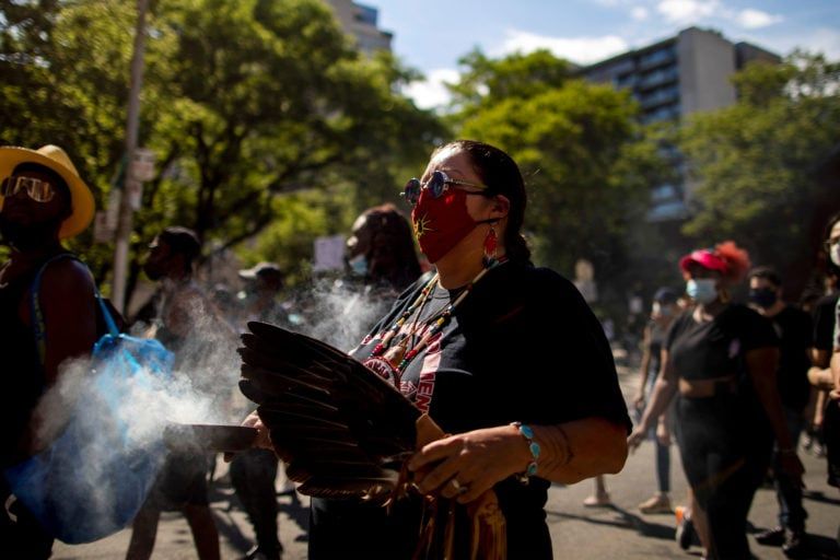 A woman carries sage as people take part in an "abolish the police sit-in" in Toronto in June (Carlos Osorio/Reuters)