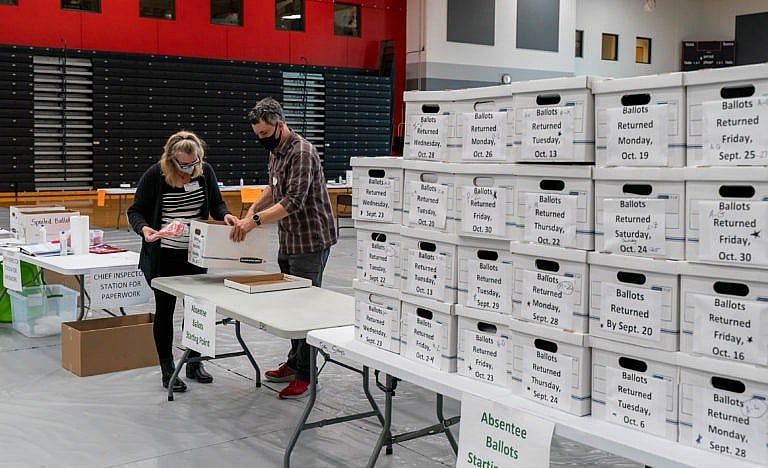Poll workers Angela and Zach Achten check-in a box of absentee ballots in the gym at Sun Prairie High School on November 3, 2020 in Sun Prairie, Wisconsin. The entire gym was dedicated to counting the absentee ballots. (Andy Manis/Getty Images)