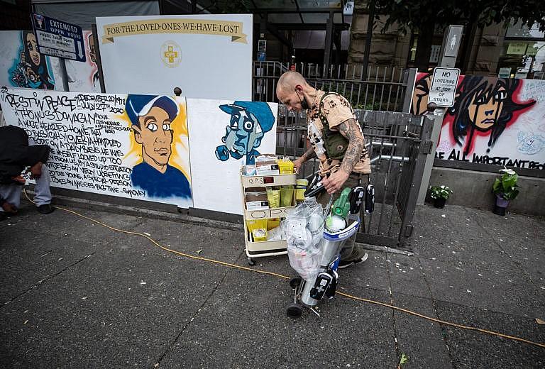 A man wheels oxygen and supplies to a safe injection site in Vancouver’s Downtown Eastside (Darryl Dyck/CP)