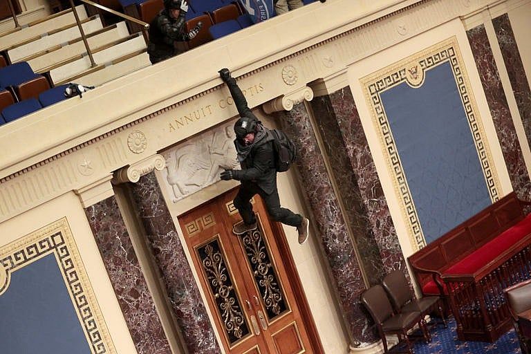 A protester hangs from the balcony in the Senate Chamber on Jan. 06, 2021 in Washington, DC (McNamee/Getty Images)