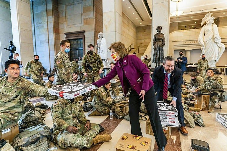 Rep. Vicky Hartzler, R-Mo., and Rep. Michael Waltz, R-Fla., hand pizzas to members of the National Guard gathered at the Capitol Visitor Center, Wednesday, Jan. 13, 2021, in Washington. as the House of Representatives continues with its fast-moving House vote to impeach President Donald Trump, a week after a mob of Trump supporters stormed the U.S. Capitol. (Manuel Balce Ceneta/AP/CP)
