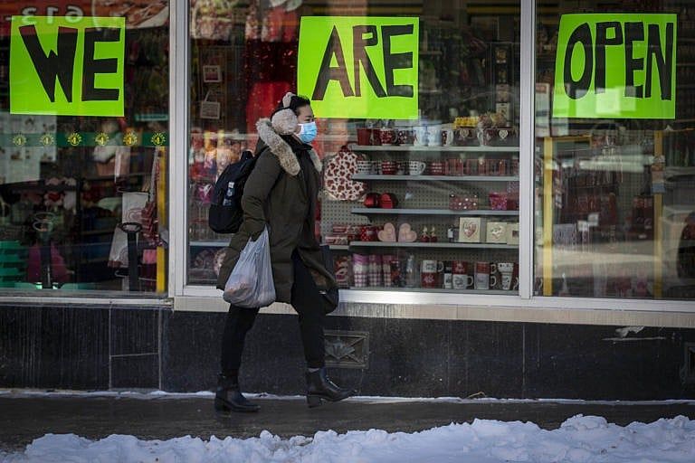 A person wears a mask to protect them from the COVID-19 virus while walking by an open store in Kingston, Ontario, on Wednesday Feb. 10, 2021. Kingston, Frontenac and Lennox &amp; Addington (KFL&amp;A) Public Health unit has moved into the green zone. THE CANADIAN PRESS/Lars Hagberg