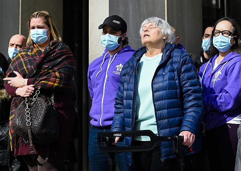 Survivor Cathy Ridell, second from right, takes in the sun as she stands with family and friends as they share a moment outside the courthouse after Alek Minassian had been found guilty on all 26 counts including 16 counts of attempted murder and 10 counts of first-degree murder for the Toronto van attack, in Toronto, Wednesday, March 3, 2021. The verdict was streamed live on YouTube due to the COVID-19 pandemic. (Nathan Denette/CP)