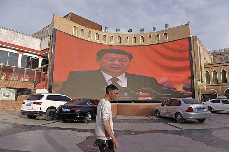 A man walking past a screen showing images of China's President Xi Jinping in Kashgar in China's northwest Xinjiang region (Greg Baker/AFP/Getty Images)
