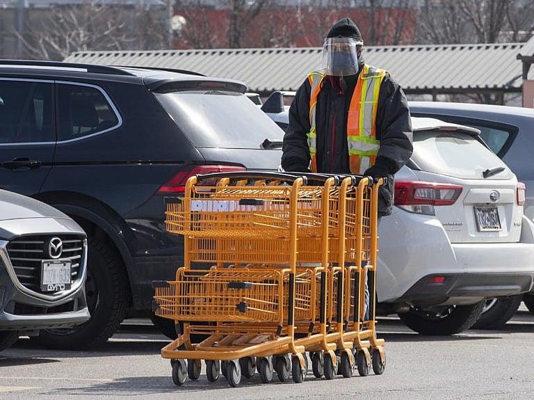 An essential worker gathers shopping carts in a grocery store parking lot in Toronto on Wednesday, March 17, 2021. THE CANADIAN PRESS/Frank Gunn