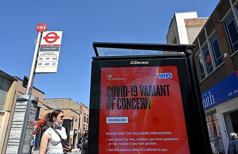 A woman waits at a bus stop byt a sign warning members of the public about a "Coronavirus variant of concern' in Hounslow, west London on June 1, 2021. - A rise in cases of the Delta Covid-19 variant, first identified in India, could "pose serious disruption" to Britain's reopening plans, Prime Minister Boris Johnson warned last week. (Photo by JUSTIN TALLIS / AFP) (Photo by JUSTIN TALLIS/AFP via Getty Images)