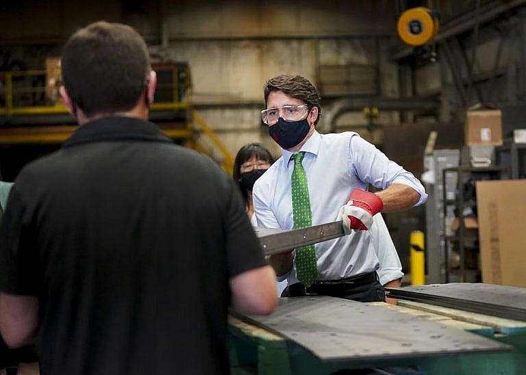 Trudeau handles a piece of steel at a campaign stop in Cambridge, Ont., on Aug. 29, 2021 (Nathan Denette/CP)