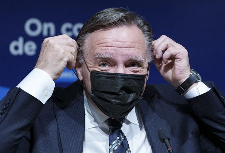 Legault slips on his mask following a news conference in Montreal, Dec. 16, 2021. (Paul Chiasson/The Canadian Press)